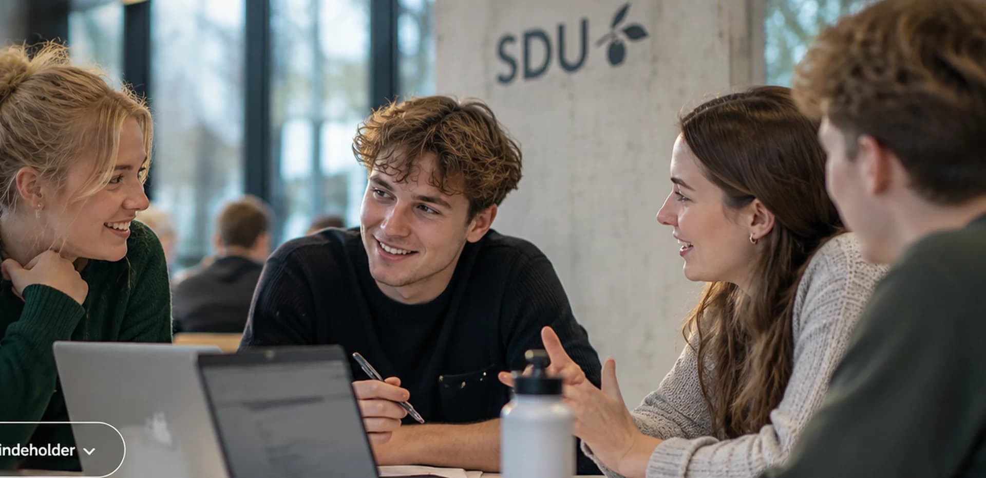 Studerende arbejder sammen om en projektopgave med laptops og noter
